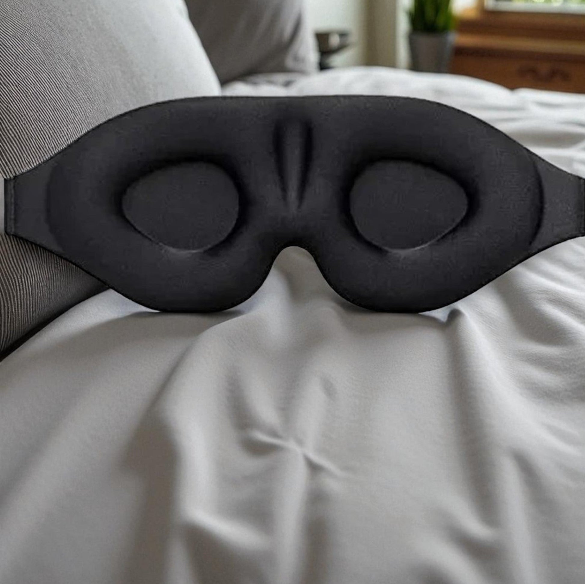 Black sleep mask on a bed in a bedroom setting